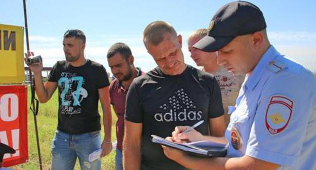 Farmers on protest rally in the Krasnosulin District and a policeman, August 12, 2018. Photo by Vyacheslav Prudnikov for the Caucasian Knot