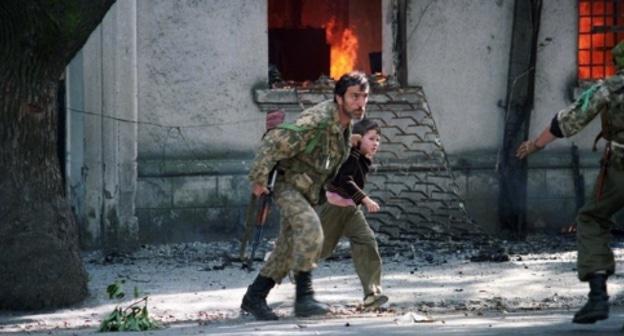 Fighter is taking a child away from the burning building in Sukhumi, 1993. Photo: Andrei Soloviev, RFE/RL