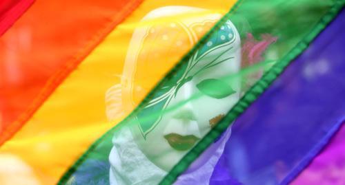 A participant of the gay parade hidden beneath the flag of LGBT. Photo Reuters/S. Ravikumar