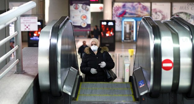 A woman in a medical mask riding an escalator. Photo: REUTERS/Sergio Perez