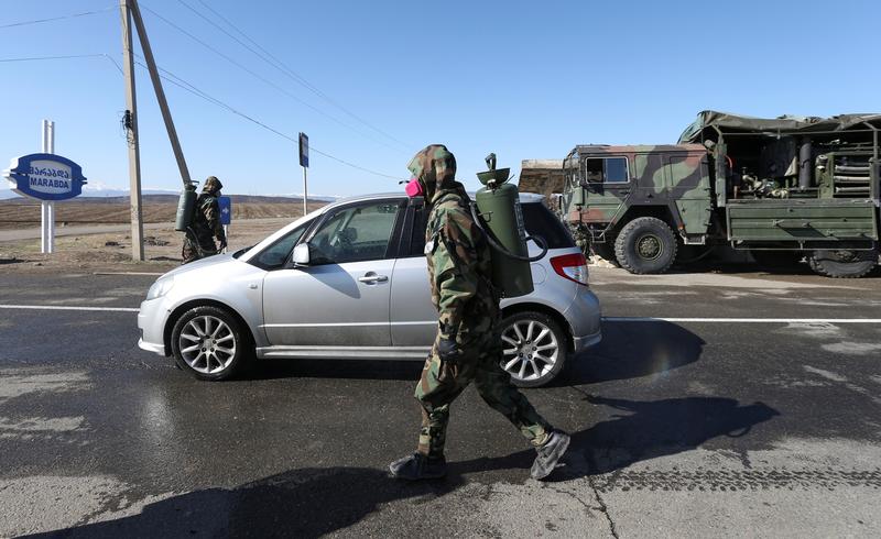 A cleaning services specialist disinfects streets in the village of Marabda. March 23, 2020. Photo: REUTERS/Irakli Gedenidze