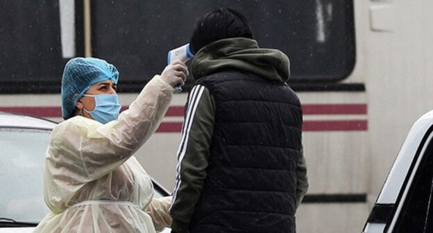 Medical worker measuring temperature. Photo: Hayk Baghdasaryan/Photolure via REUTERS