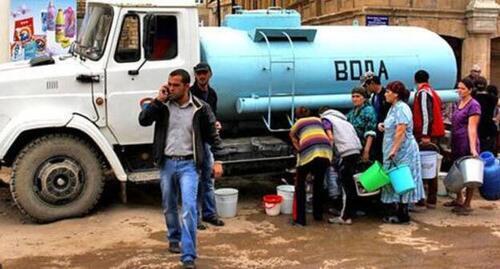 People stand in line at a vehicle with water, Dagestan. Abstract illustration. Photo by Makhach Akhmedov for the Caucasian Knot