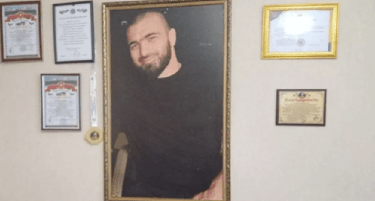 Kurban Dalgatov's photo at his parents' home. Photo by the "Chernovik" outlet https://chernovik.net/news/zakryl-kurtkoy-obzor-videokamery-i-telo-kurbana-potaschili-vniz